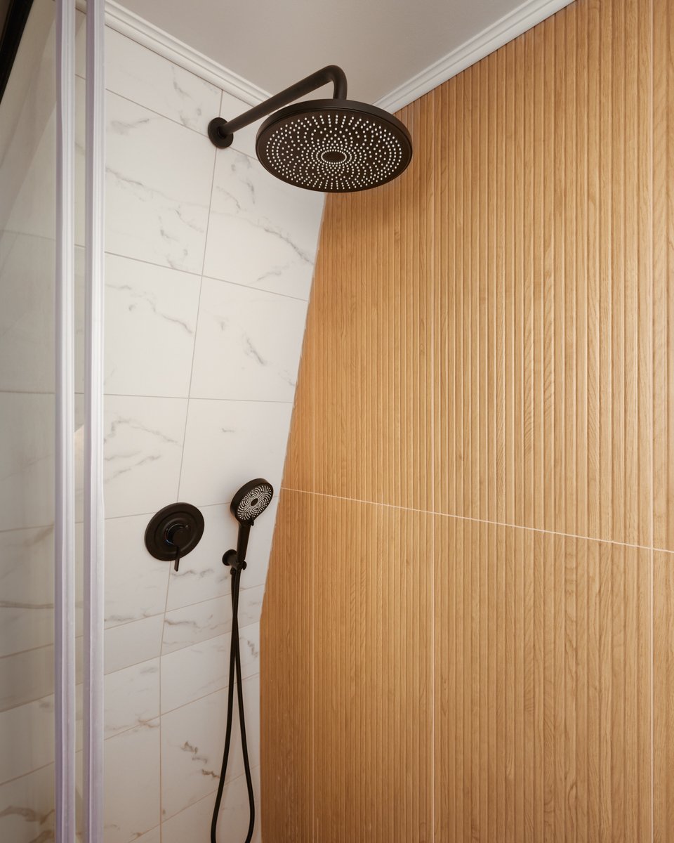 Black matte rainfall shower head and handheld sprayer against marble tile and wood slat wall in the finished Jay bathroom