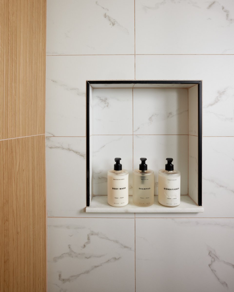 Built-in marble shower niche with amenity bottles in the finished Jay bathroom