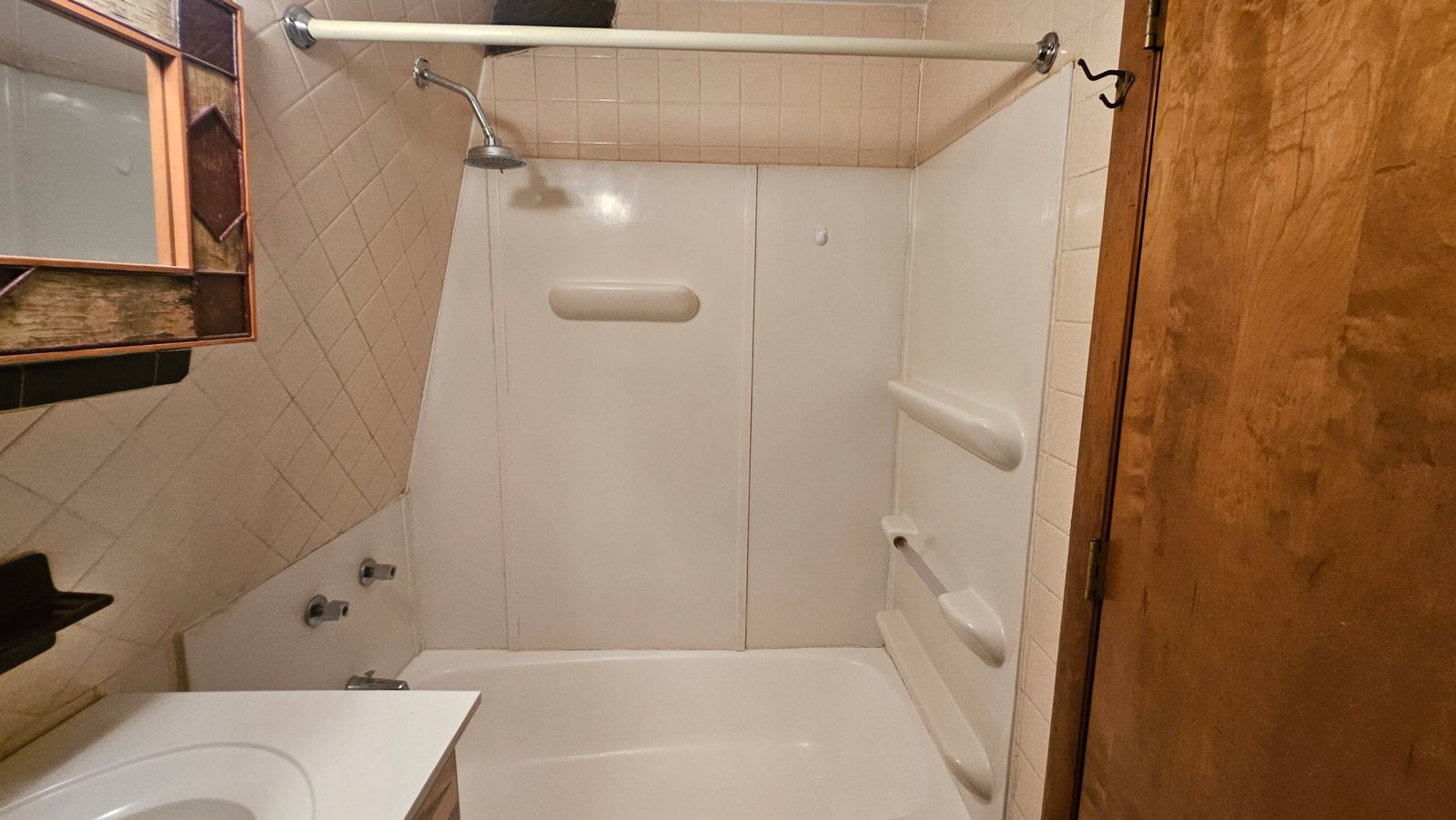 Old tub-shower combo in the Jay bathroom before renovation, dated fiberglass surround and diamond tile