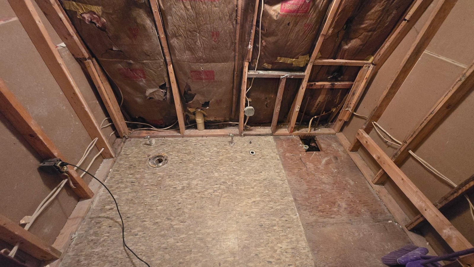 Jay bathroom gutted to the studs on demo day, original subfloor and plumbing stubs exposed